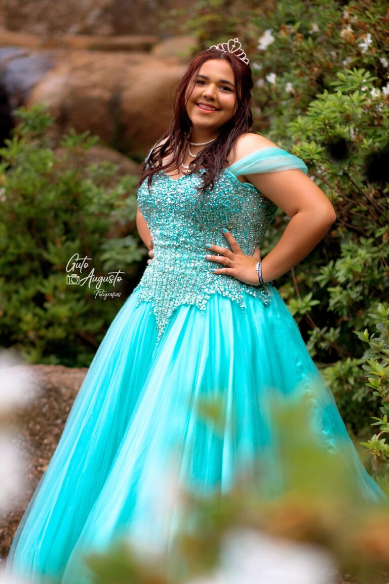 Alana posando em seu ensaio de 15 anos, com um lindo vestido azul e tiara, capturada em meio à natureza por Guto Augusto Fotografias.